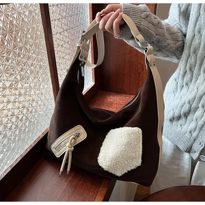 Detail of vintage brown suede tote bag featuring a white faux fur pocket and long tassels