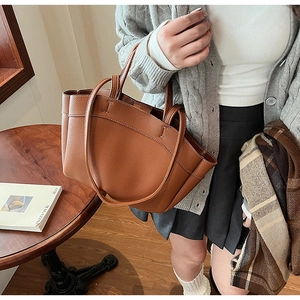 Brown litchi grain tote bag with double handles shown in a warm indoor lifestyle setting