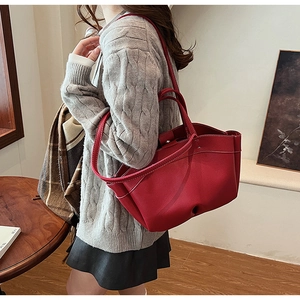 Detail of burgundy tote bag with contrast stitching and magnetic closure on shoulder