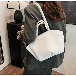 Detailed view of the white textured leather handbag with elegant pleated wing design