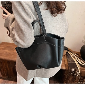 Detail of black leather tote bag with white contrast stitching and side pleat design