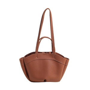 Detail of brown lychee texture leather bag with contrast stitching and dual straps
