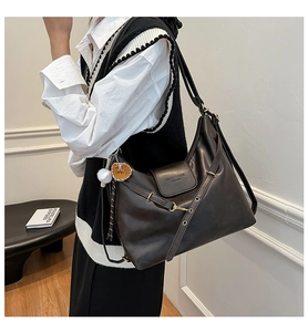 Detail of dark brown leather tote bag with metal ring closure and sporty ball pendant
