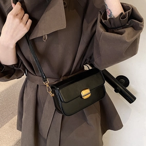 Petit sac carré noir rétro avec boucle dorée et bandoulière réglable porté par un mannequin