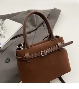 Detail view of suede tote bag in dark brown with belt buckle and top handle