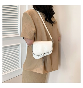 Détail du sac selle blanc avec rivets argentés et franges métalliques sur un mannequin