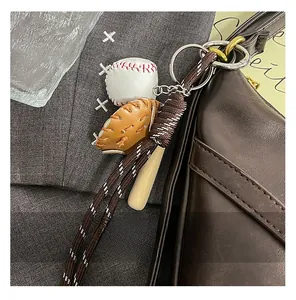 Macro detail of baseball glove and bat keychain charm on a brown leather shoulder bag