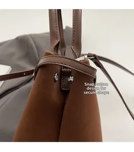Macro detail of silver snap button design and matte brown leather texture on bucket bag