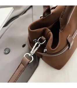 Detail of silver metal hook and suede strap on a dark brown leather tote bag