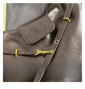 Detailed close-up of dark brown leather bag with vintage gold ring and metallic hook buckle