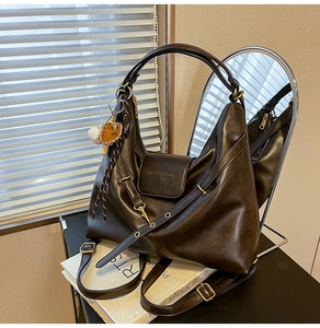 Detail of dark brown leather hobo bag with baseball glove charm and MUONSHARK engraving