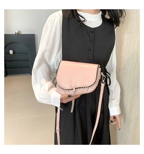 Détail du sac bandoulière rose avec rivets et gland porté par un mannequin