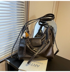 Detail view of deep brown vintage tote with brand engraving and baseball charm accessory