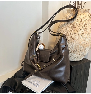 Detailed view of deep brown faux leather tote bag with unique baseball charm accessory