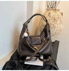 Close-up of vintage dark brown faux leather hobo bag with baseball glove pendant