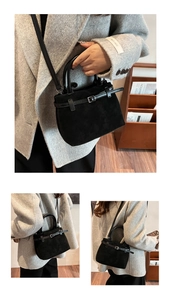 Detail of black matte crossbody bag with leather handles and metallic buckle on gray coat