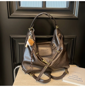 Detailed close-up of dark brown PU leather hobo bag with baseball charm and brand logo