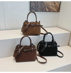 Three minimalist matte leather bucket bags in brown and black on a tiered display