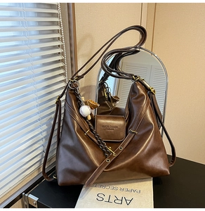 Detail of vintage brown matte leather tote bag featuring baseball charm and branding
