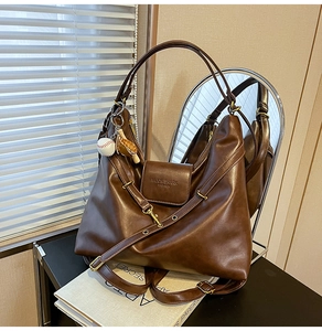 Detail of dark brown leather tote bag with embossed logo and baseball bat charm