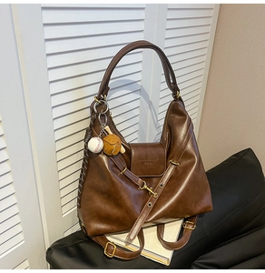 Detail of dark brown vintage leather tote bag with baseball themed charm and textured finish