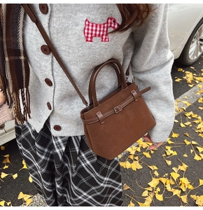 Detail of a brown matte suede bucket bag with a belt buckle on a stylish model