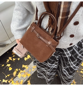 Outdoor shot of a brown vintage crossbody bag with strap on autumn leaves background