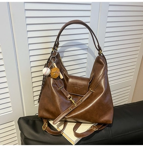 Detail of dark brown hobo bag with gold hardware and baseball themed charm accessory