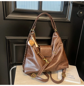 Detail of dark brown leather tote featuring vintage bronze hardware and baseball charm