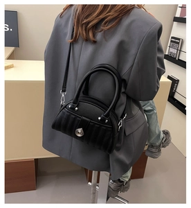 Detailed view of black quilted leather shoulder bag with silver turn-lock and chain strap