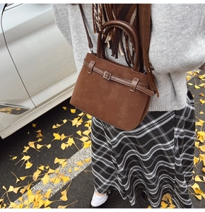 Deep brown retro crossbody bag with suede texture shown in a scenic autumn street setting