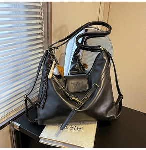 Detail of black PU leather tote with brand logo and baseball charm accessory