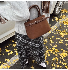 Detail of dark brown matte leather handbag with strap buckle in a retro autumn setting