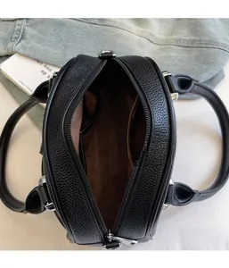 Detail view of the black lychee pattern bag showing zipper closure and brown lining