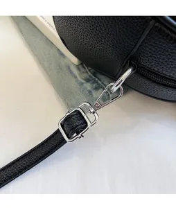 Detail of adjustable strap with silver metal buckle on black lychee texture handbag