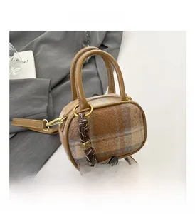 Close-up of vintage check wool texture and leather handle on a mini Boston bag