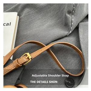 Detail of adjustable brown leather shoulder strap with gold buckle and white stitching