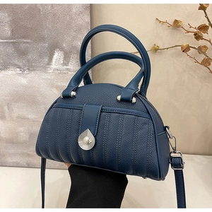 Detail of navy blue pebble leather handbag with silver teardrop clasp and quilted texture