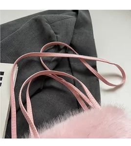 Détail du sac à bandoulière en fausse fourrure rose avec une longue sangle lisse