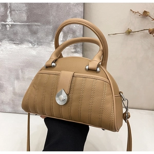 Detail of khaki pebbled leather handbag featuring silver teardrop metal decor and stitching