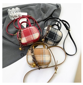 Flat lay of plaid woolen mini bowling bags in red, black, and khaki with decorative charms