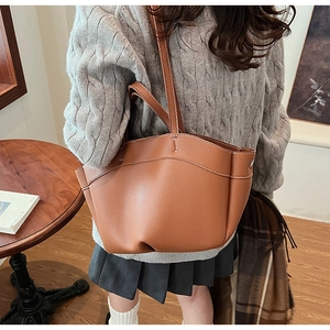 Caramel brown pebbled leather tote bag worn by a model in a minimalist vintage style