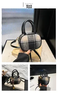 Close-up of black plaid wool mini bowling bag with leather handles and gold metal hardware