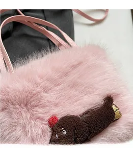 Détail d'un sac à main en peluche rose avec fourrure douce et un petit ours brun décoratif