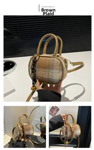 Detail of mini plaid bowling bag featuring leather handles and woven knot keychain