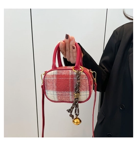 Close-up of red and white checkered bowling bag with bell charm and leather strap