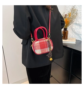 Detail of red and white plaid bowling bag with woven charm and golden bell