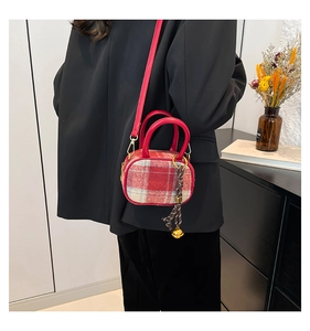 Detail of red and white checkered bowler bag featuring a golden bell charm and strap