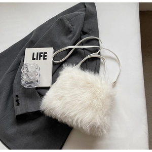 Détail de la texture d'un sac à bandoulière en fausse fourrure blanche et fines anses
