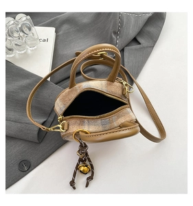 Close-up of contrast stitching beige leather and plaid fabric bowling bag with gold hardware